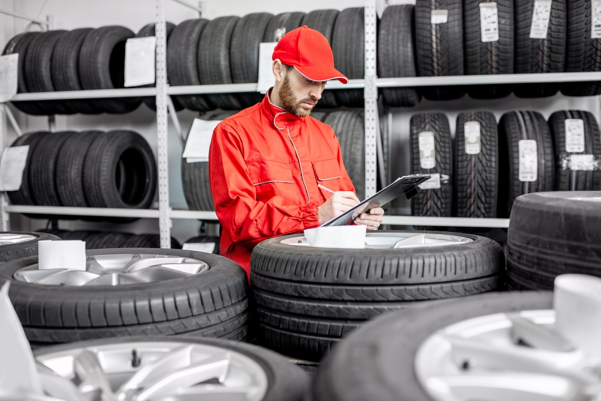 Man in red with clipboard surrounded by tires.