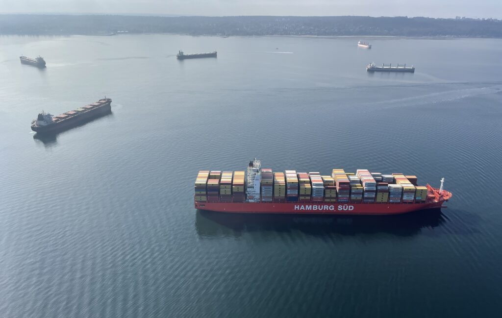 Six container ships are anchored close to each other in the Salish Sea.