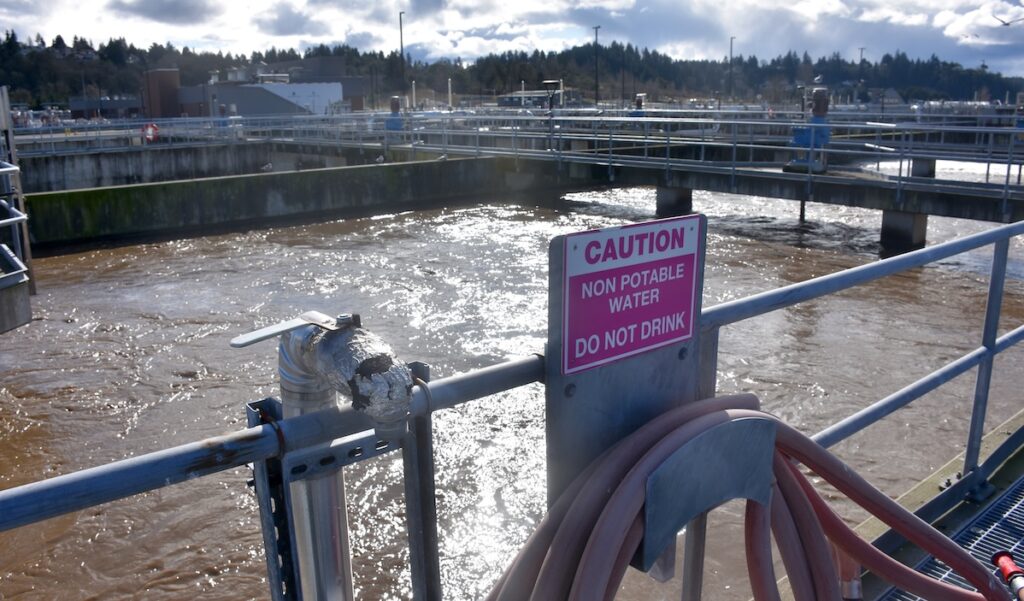 Sign on aeration tank railing reading "Caution: Non-Potable Water — Do Not Drink."